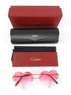 Cartier sunglasses with pink lenses and heart shape, accompanied by a black case and red box on a white background.