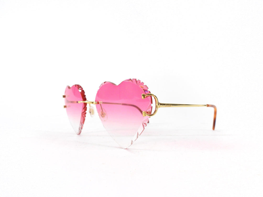 Heart-shaped sunglasses with pink gradient lenses and gold frame on a white background