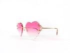 Heart-shaped sunglasses with pink gradient lenses and gold frame on a white background