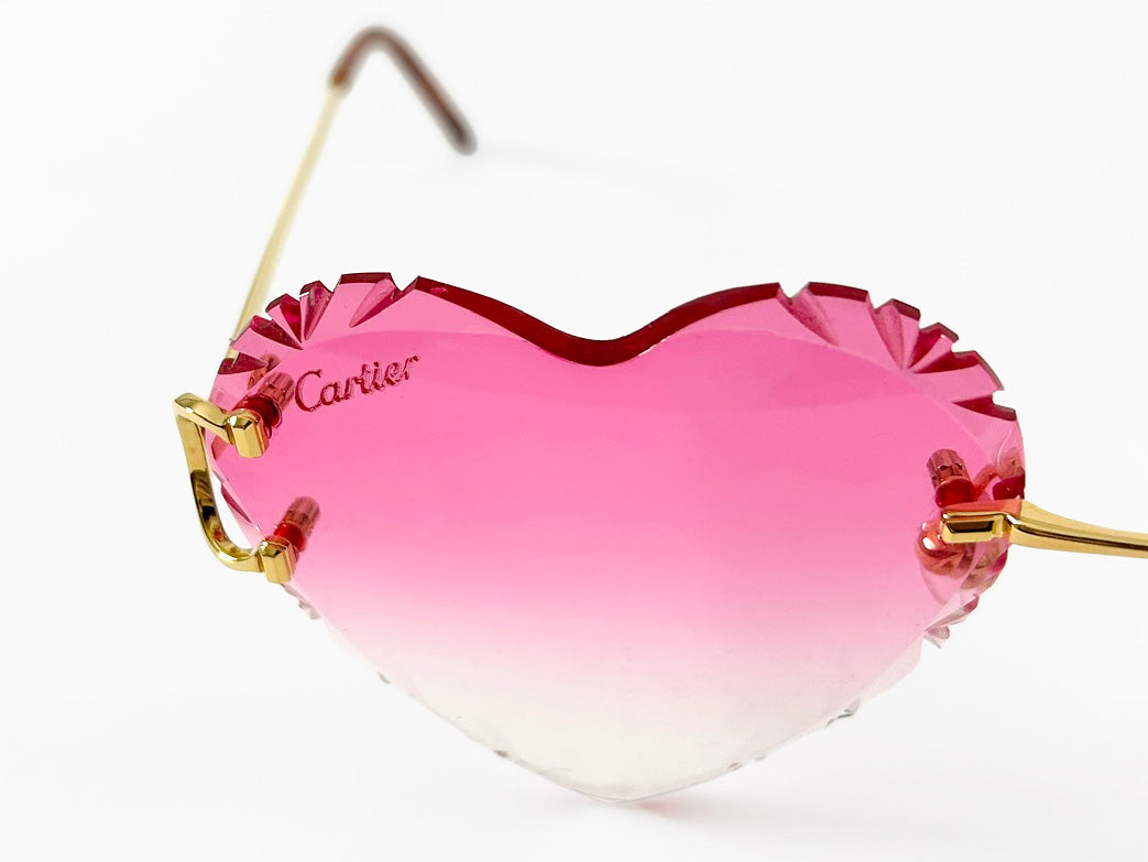 Cartier heart-shaped sunglasses with pink gradient lenses on a white background
