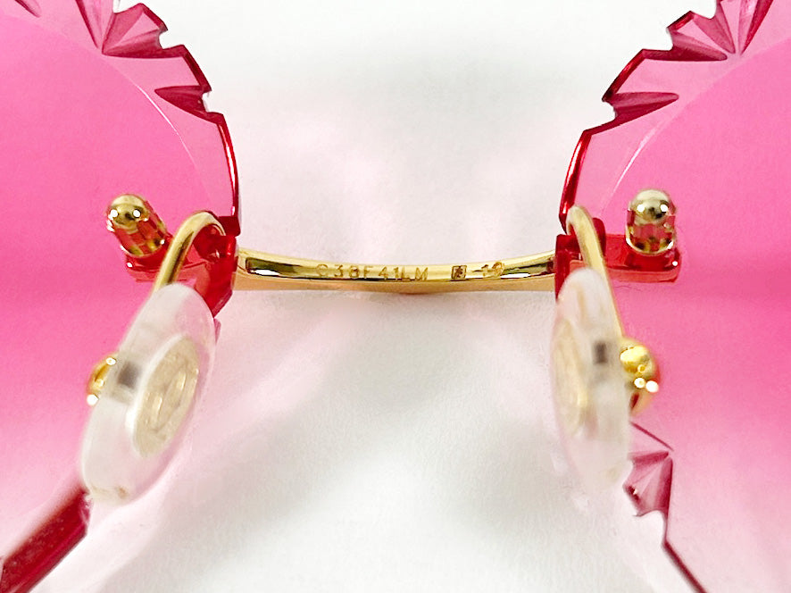 Close-up of pink sunglasses with gold frames on a white background