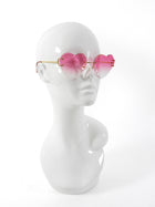 Sunglasses with pink heart-shaped lenses on a mannequin head against a white background