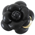 Black leather flower-shaped brooch with a gold accent on a white background