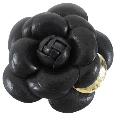 Black leather flower-shaped brooch with a gold accent on a white background