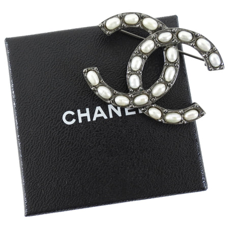 Chanel brooch with pearl accents on a black Chanel box