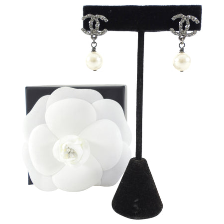Chanel earrings on a black stand with a white flower display