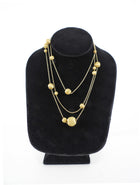 Gold necklace on a black velvet stand against a white background