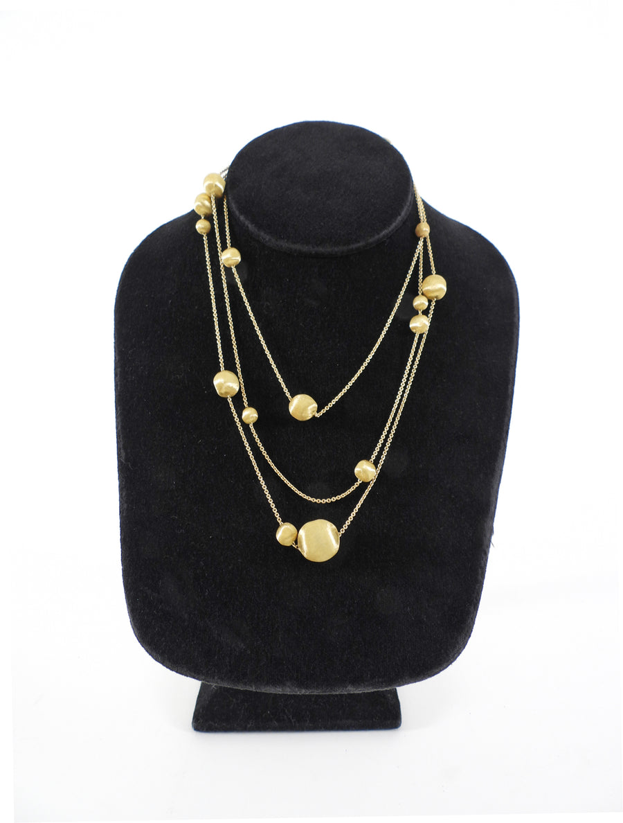 Gold necklace on a black velvet stand against a white background