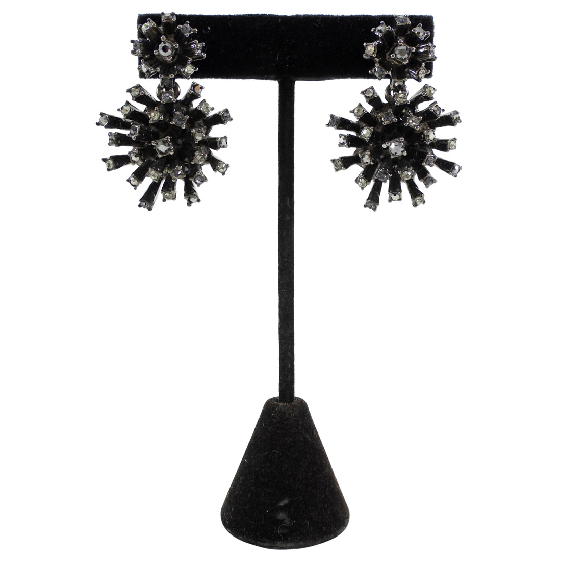 Black and silver earrings on a black stand against a white background