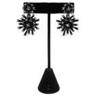 Black and silver earrings on a black stand against a white background