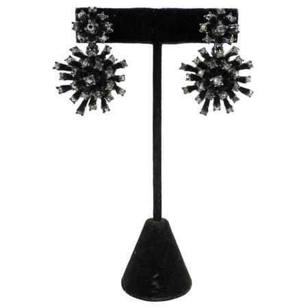 Black and silver earrings on a black stand against a white background