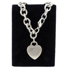 Tiffany & Co. Silver chain bracelet with a heart-shaped pendant on a black velvet stand.
