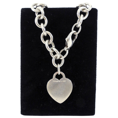 Tiffany & Co. Silver chain bracelet with a heart-shaped pendant on a black velvet stand.