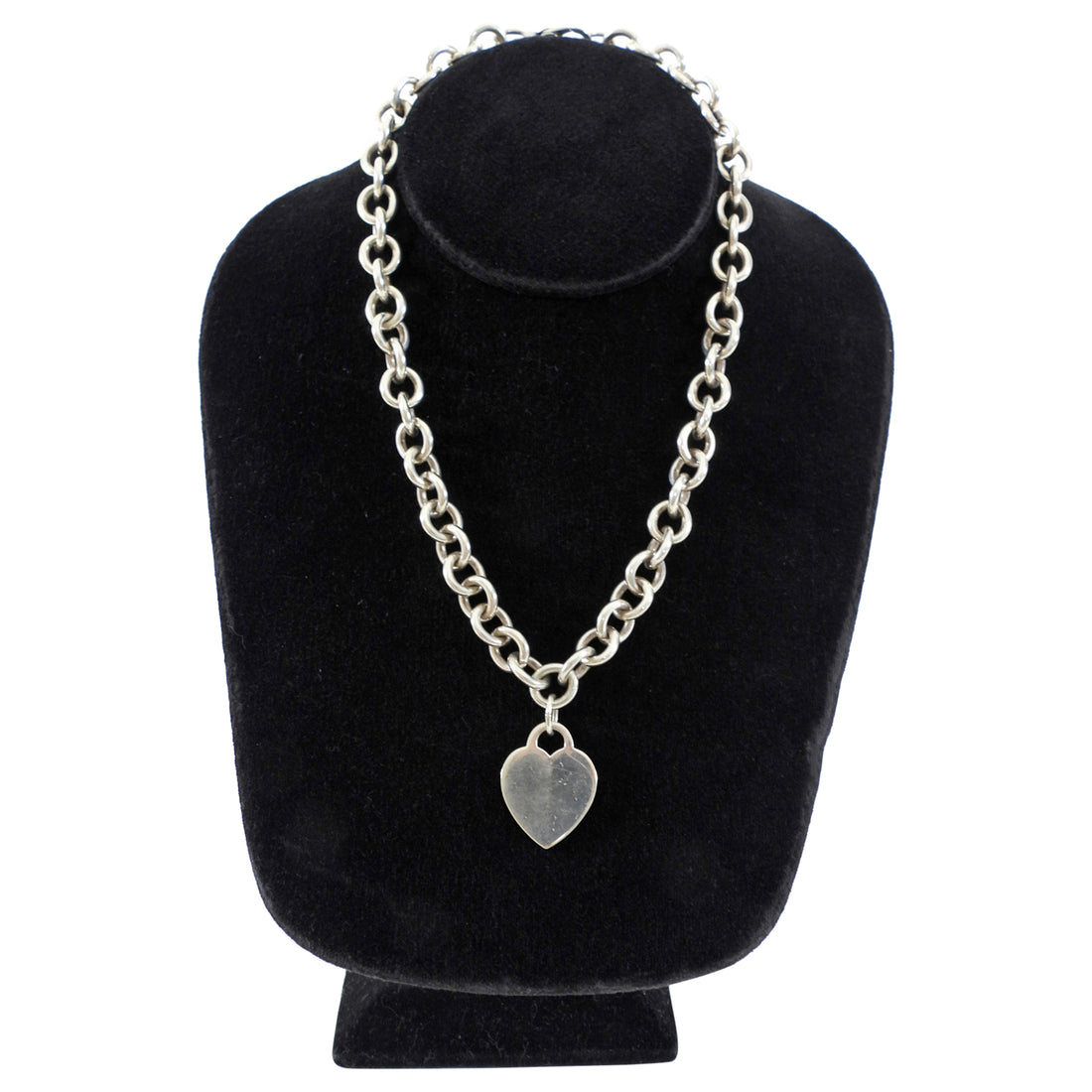 Tiffany & Co. Silver chain necklace with a heart pendant on a black velvet stand.