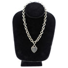 Tiffany & Co. Silver chain necklace with a heart pendant on a black velvet stand.